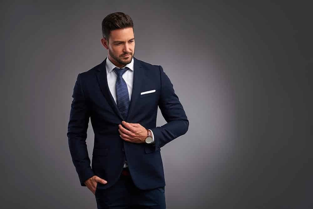 Man in donkerblauw pak knoopt zijn jasje dicht